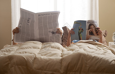 床上的情侣男性妻子团结羽绒被阅读已婚夫妇年轻人女性家居图片