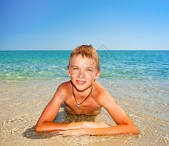 男孩在海滩上童年假期快乐闲暇棕褐色游泳衣娱乐孩子阳光海滨图片