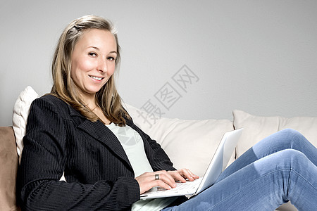 妇女用笔记本电脑在沙发上工作互联网快乐女孩白色技术女士成人房间黑发图片