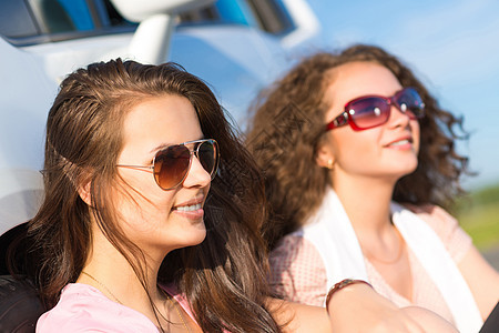 两名身戴墨镜的年轻美女树干车辆日落享受家庭天空情侣幸福女性男人背景图片