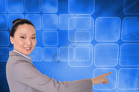 笑笑的亚洲女商务人士指着一副综合图像职业网格人士计算界面套装未来派触摸屏计算机女性图片