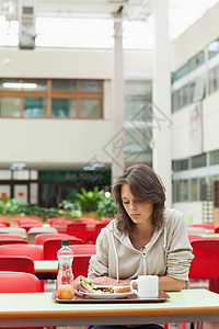 餐厅里带着食物托盘的悲哀学生茶点忧郁杯子孤独头发椅子悲伤饮料女性早餐图片