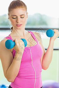 健身工作室中适合运动的女子在健身房用哑铃锻炼减肥调子浅色女性肌肉重量耳机音乐金发女郎金发图片