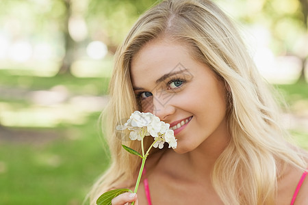 美丽的金发美女 在公园里闻着一朵花的香味图片
