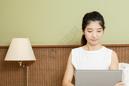 在卧室用笔记本电脑工作的年轻快乐的年青女士女性说谎女孩冲浪技术白色黑发闲暇地面互联网图片