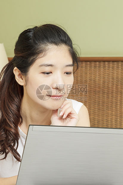 在卧室用笔记本电脑工作的年轻快乐的年青女士冲浪说谎黑发女孩白色互联网闲暇地面女性技术图片