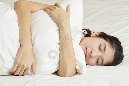 睡在床上的年轻美女寝具白色女孩卧室女性闲暇女士牙裔睡衣枕头图片