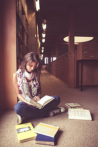 女学生在图书馆走道读一本书棕色房间围巾学生双腿地面倾斜女性书架文学图片