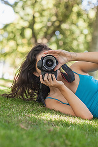 躺在草坪上拍照的年轻黑发女人图片