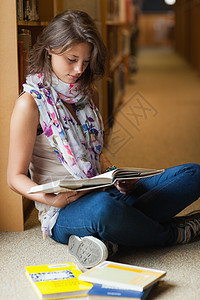 女学生在图书馆走道读一本书学生倾斜教育专注架子头发学习文学牛仔裤书架图片