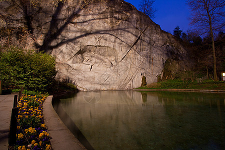 在瑞士卢塞恩的死狮子纪念碑 花朵照亮闪耀图片