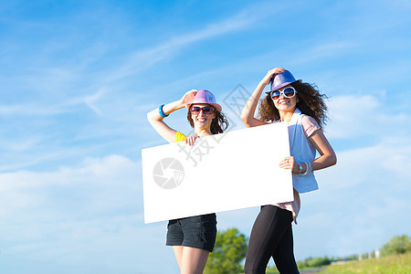 两名年轻女性站在空白的横幅上站着女孩天空自由旅行便车冒险假期路线旅游成人图片