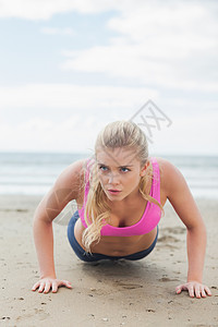 美丽的女人在沙滩上做俯卧撑金发女郎运动服护理热身闲暇调子肌肉身体运动员双手图片