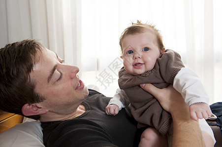 年轻父亲抱着他的女婴微笑关系女儿卧室孩子父母女孩爸爸纽带惊喜图片