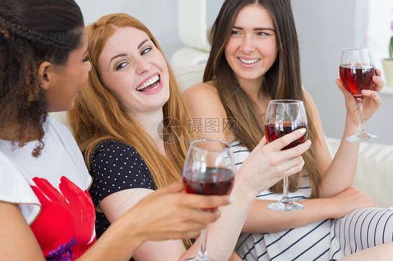 带着葡萄酒杯的快乐女朋友 享受谈话愉快派对幸福浅色酒精朋友们公寓头发睡衣互动沙发图片