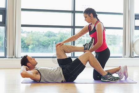 女教练员协助男子在体操中锻炼训练男性护理拉伸讲师运动瘦身闲暇运动垫帮助图片