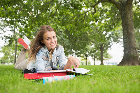 躺在草地上学习的快乐青年学生图片