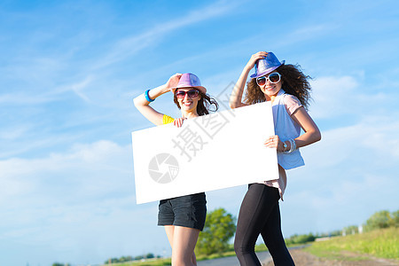 两名年轻女性站在空白的横幅上站着木板远足者游客路线天空冒险成人季节女士航程图片