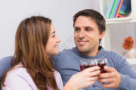 在家喝红酒杯时笑一笑的情侣女性亲热幸福男人酒精男性公寓微笑客厅棕色图片