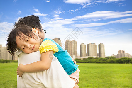 微笑的小女孩睡在城市公园的父亲肩上睡觉图片