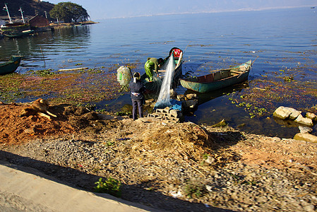 中国云南省达利埃海尔湖捕鱼者食物爬坡镜子独木舟天空风景蓝色漂浮工作渔夫图片