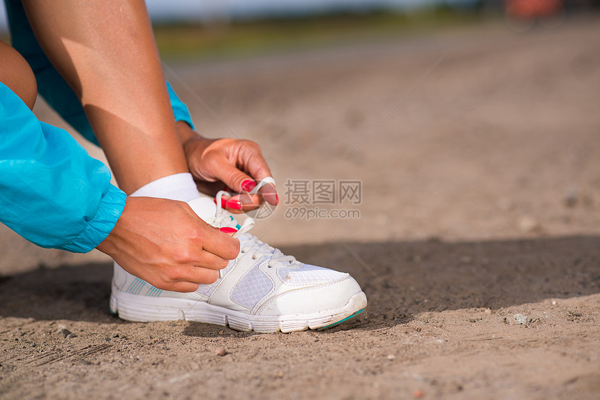 年轻女子在运动鞋上系鞋带活力行动跑步闲暇蓝色力量成人赛跑者海滩女孩图片