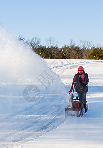 高级妇女与吹雪者清扫车驾驶人行道降雪车道女士工作打扫机械天气暴风雪图片