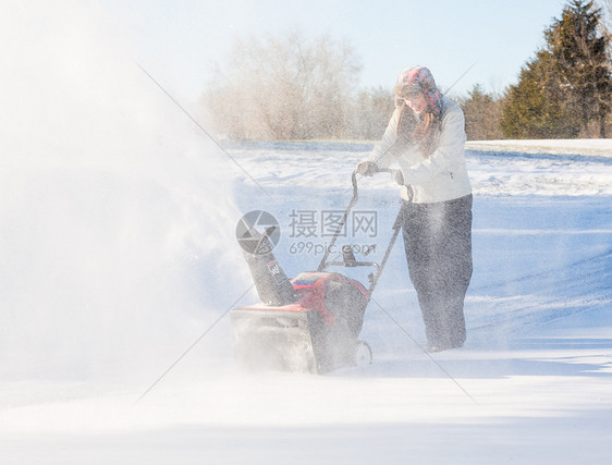 年轻妇女与吹雪者清扫车天气打扫驾驶人行道工作车道暴风雪季节机械住宅图片