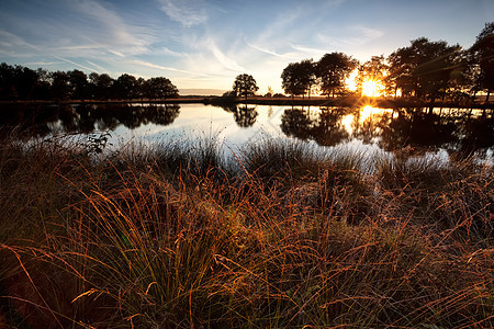 日落时在野湖上空的恒星太阳光束图片