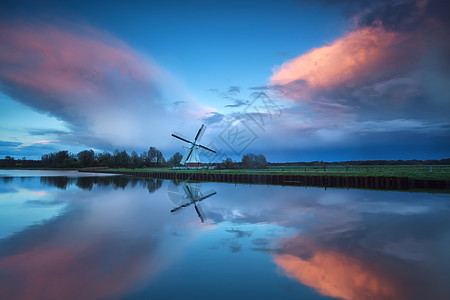 荷兰风车和河流上空的暴雨日落图片