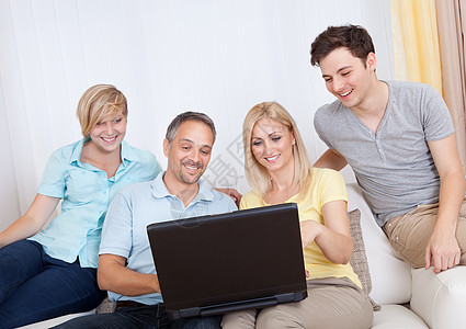 家人一起坐在沙发上 用笔记本电脑展示母亲父母姐姐购物长椅女儿父亲男性互联网图片