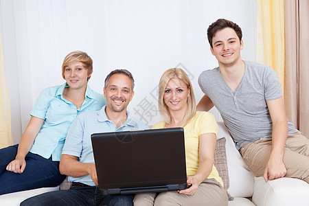 家人一起坐在沙发上 用笔记本电脑展示互联网购物兄弟男人母亲父母长椅女士手指图片
