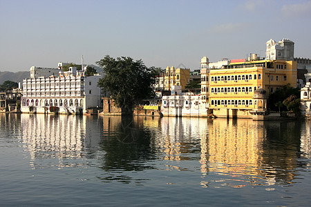 印度拉贾斯坦邦皮乔拉湖和乌代普尔市城市历史蓝色反射建筑学孔雀全景天空建筑黄色图片