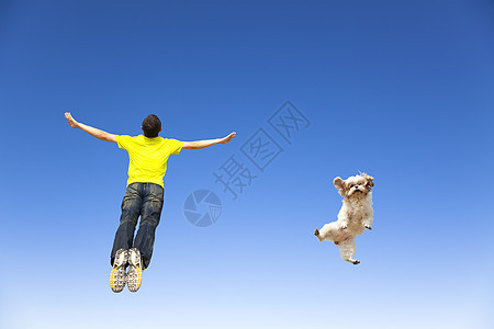 年轻人和狗在天空中跳跃蓝色活力幽默行动跑步姿势运动男人宠物乐趣图片
