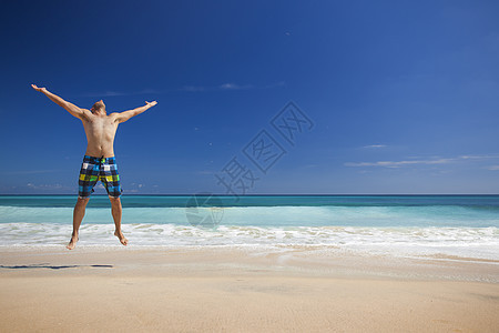 男人在海滩上跳跃幸福男性蓝色喜悦闲暇热带游泳衣旅行假期乐趣图片