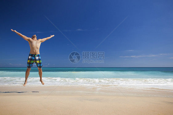 男人在海滩上跳跃幸福男性蓝色喜悦闲暇热带游泳衣旅行假期乐趣图片