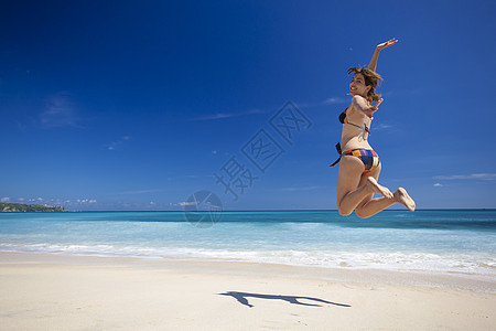 女人在海滩上跳跃成功比基尼幸福热带蓝色天空女孩乐趣海洋太阳图片