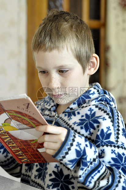 10岁的男孩坐在教科书旁边做功课 笑声孩子青少年阅读学习教训图片