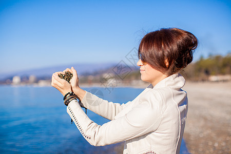 手握着小石头的女子 形成心形形状背景 海海海洋蓝色身体岩石宏观假期海岸情调手镯手指图片
