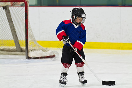 在冰球练习中带冰球滑冰的儿童图片