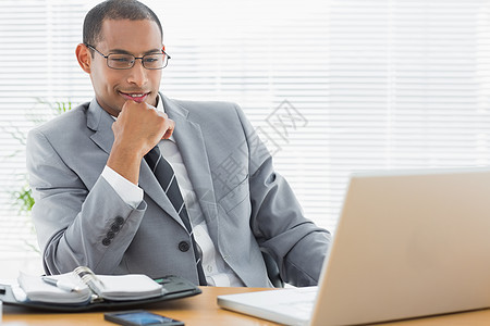 坐在办公服务台用膝上型电脑坐着的商务人士图片