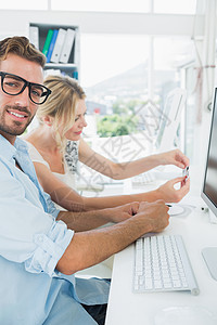 从事计算机工作的微笑的零散年轻夫妇商业设计师同事技术女士团队办公室桌子便服键盘图片