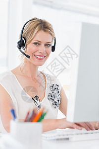使用计算机佩戴头盔的随意妇女肖像办公室代理人电脑沟通耳机中心商业键盘女性客户图片