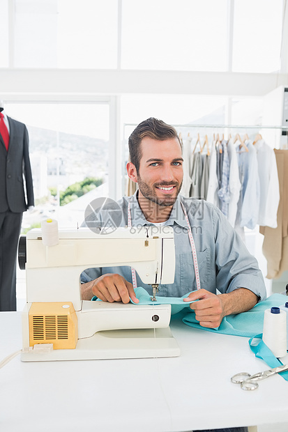在车间缝纫时微笑男性裁缝卷尺快乐纺织品剪裁手工作坊定制自雇工作室工艺图片