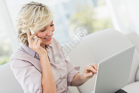 使用移动电话和膝上型电脑的女商务人士居家拨号商务手机电话技术呼唤公寓女性房子图片
