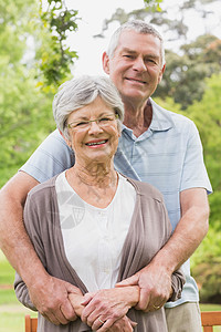 高级男子从后面的公园里抱女人夫妻闲暇享受女性老年成人树木男人亲热感情图片