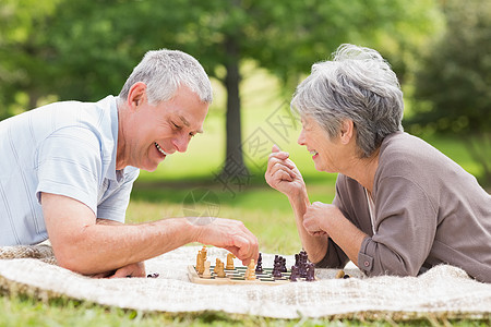 快乐的老夫妇在公园下棋地毯棋盘退休夫妻女士老年说谎享受农村闲暇图片