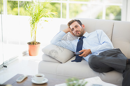 在客厅看电视的穿好衣服的男人遥控闲暇衬衫沙发领带家庭生活房子男性裤子娱乐图片