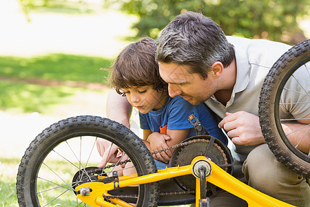 父亲和儿子修自行车男人家长身份维修车轮孩子成人男生学习帮助图片