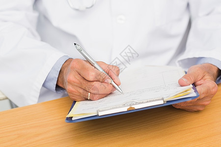 医生坐在桌子上写剪贴板写作办公室实验职场医师医疗诊所医疗保健卫生医务室图片
